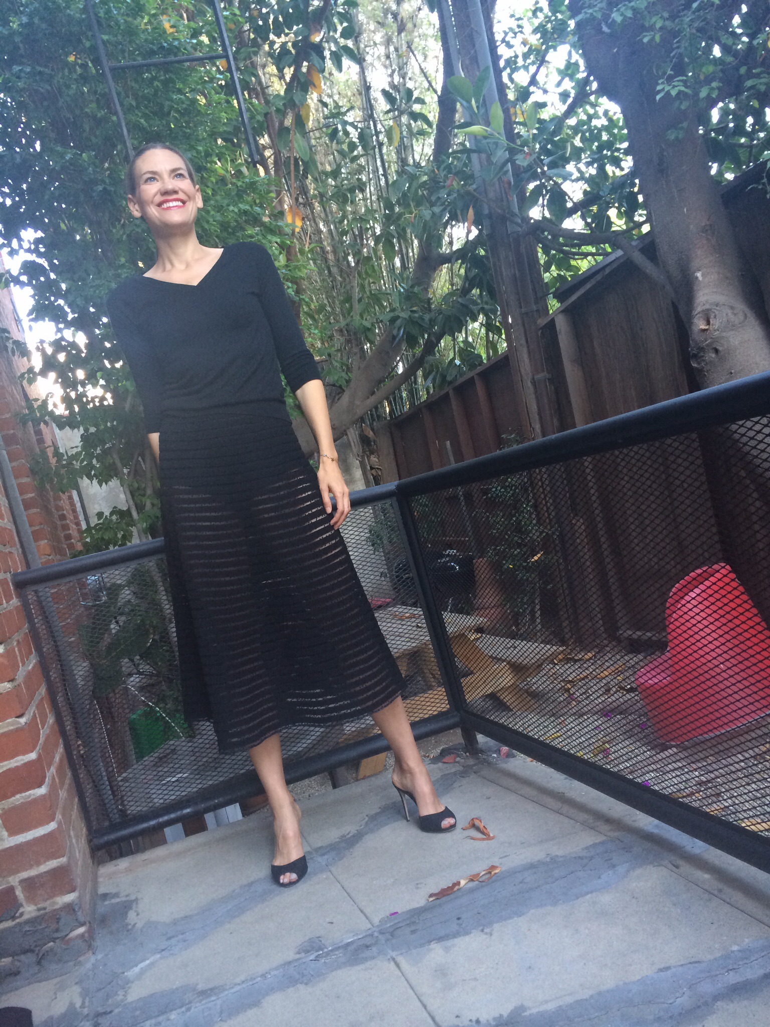 a woman in a black sweater and a sheer skirt with heels