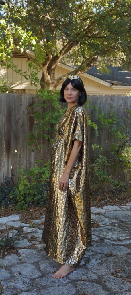a woman in a gold caftan and a gold headpiece
