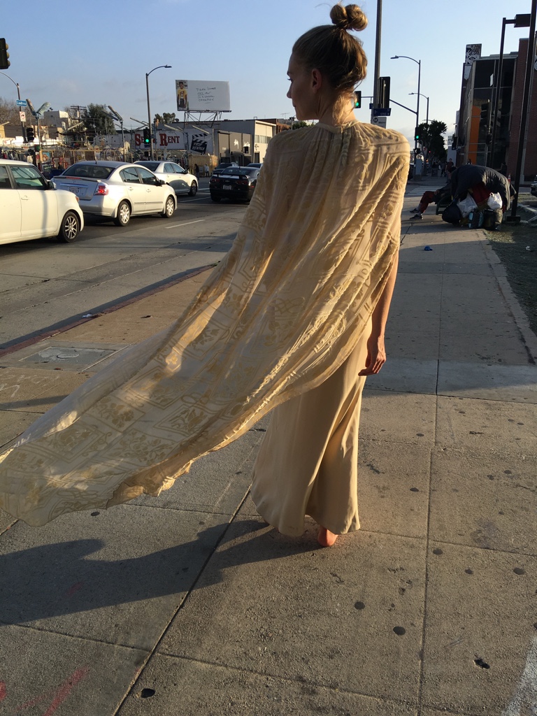 a woman in a cream silk dress with a velvet cape