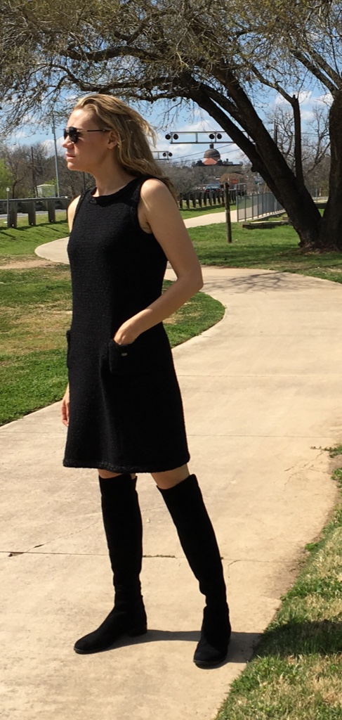 a woman in a black tweed dress and flat black boots 