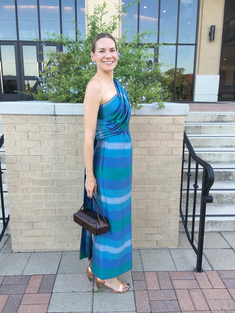 a woman in a green and blue and purple striped dress with a shoulder drape