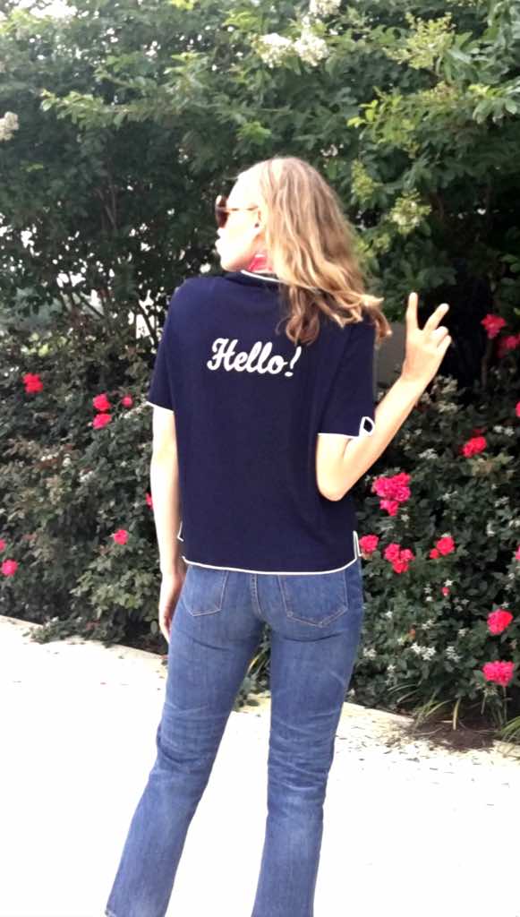 a woman in a navy knit top with hello on it in and jeans