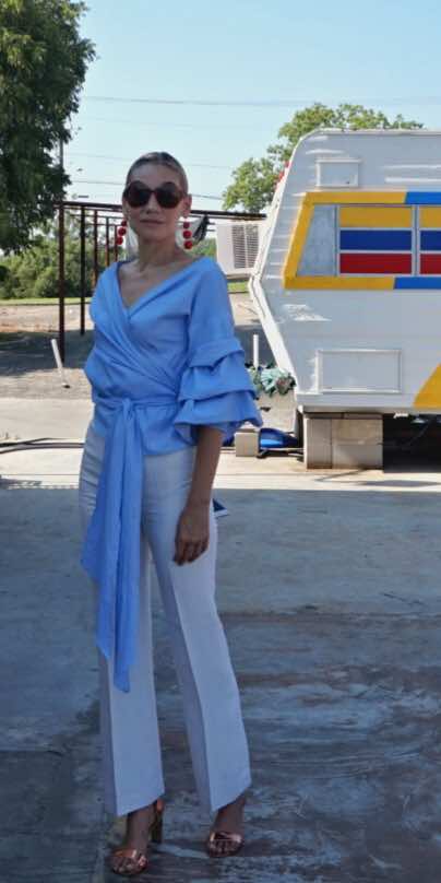 a woman in white pants and a blue wrap top in a food truck park