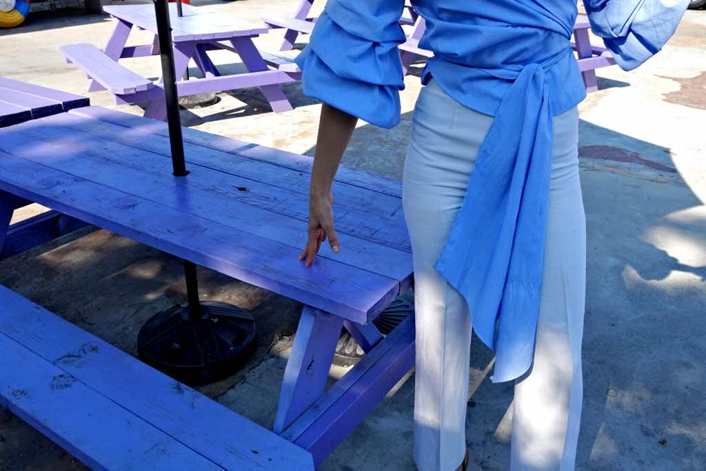 close up of a woman in white pants and a blue and white stripped top in front of a picnic table
