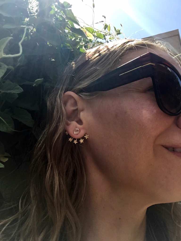 a close up of a woman's face with a star earring and sunglasses
