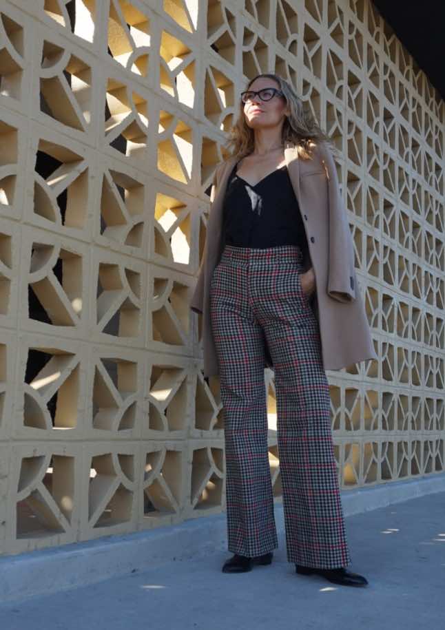 a woman in plaid pants with a black silk cami and a camel coat