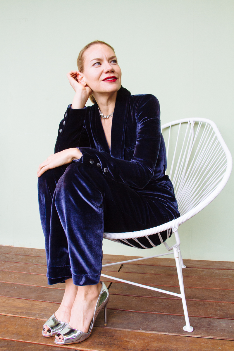 a woman in a white chair wearing a blue velvet suits