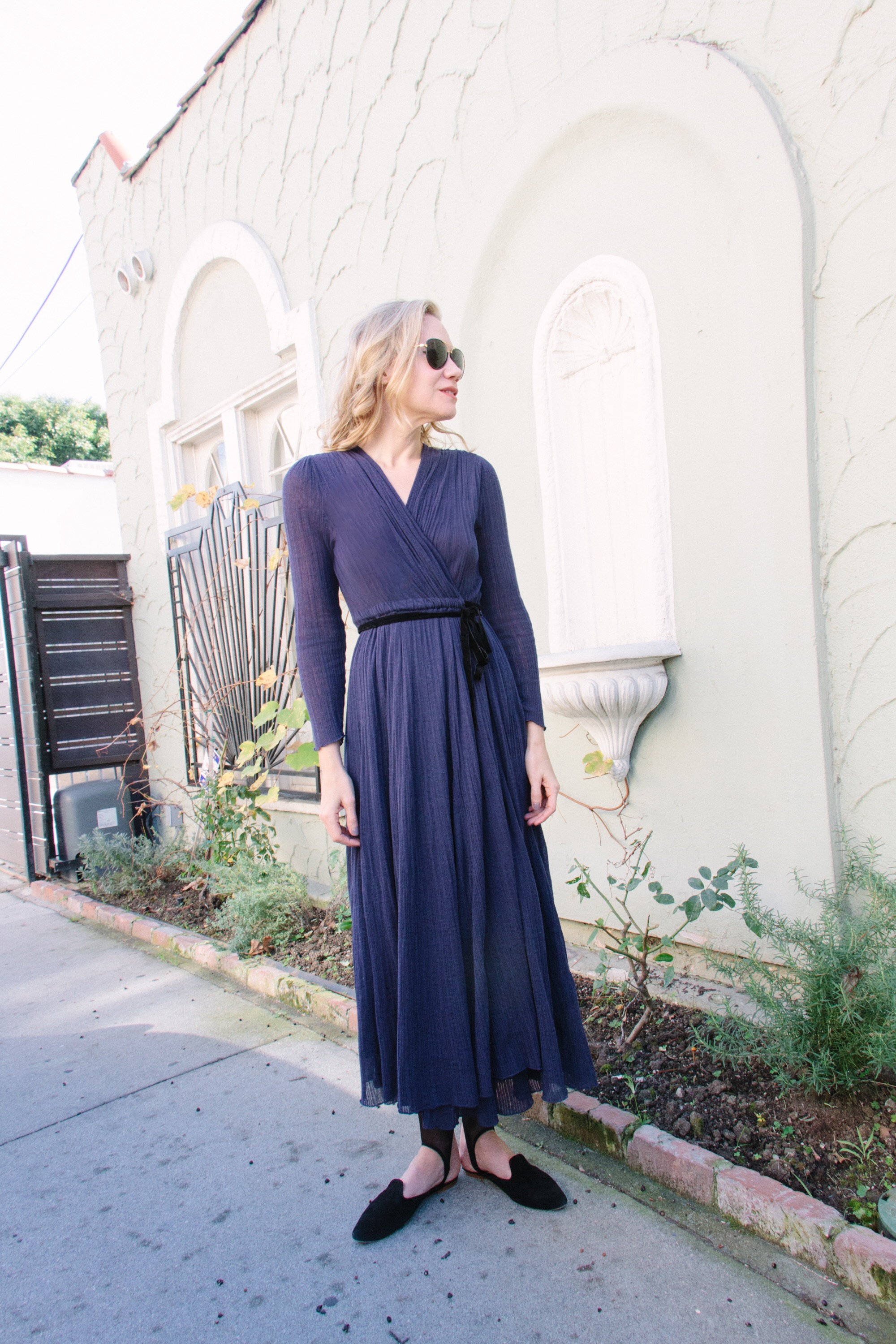 a woman in a wrap purple dress and black mules 