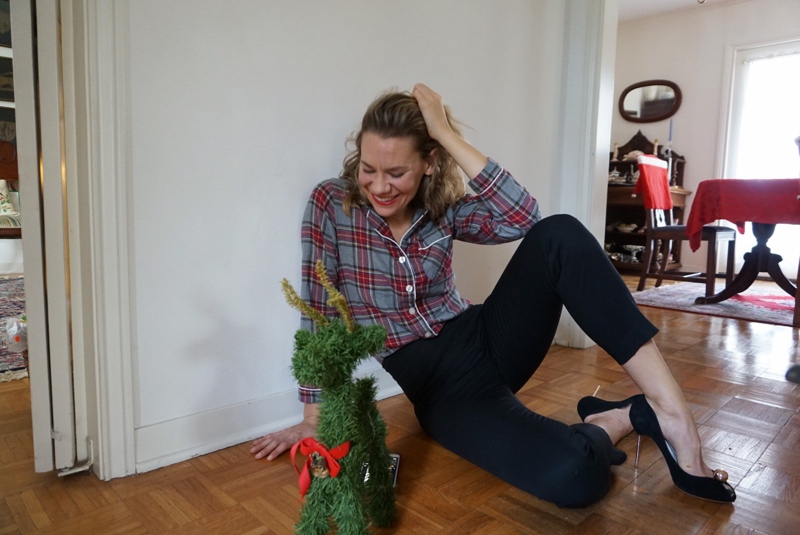 a woman in a plaid shirt and black pants sitting by a green reindeer
