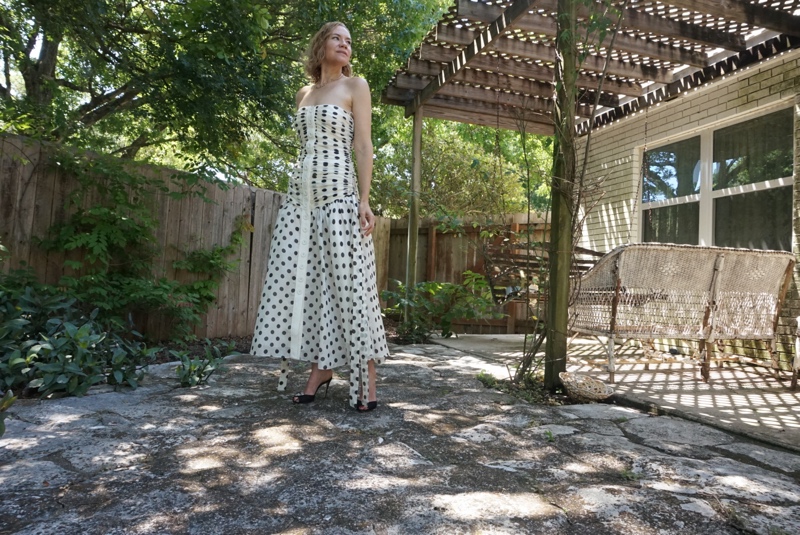  A woman in a white strapless dress with black polka dots and black heels 