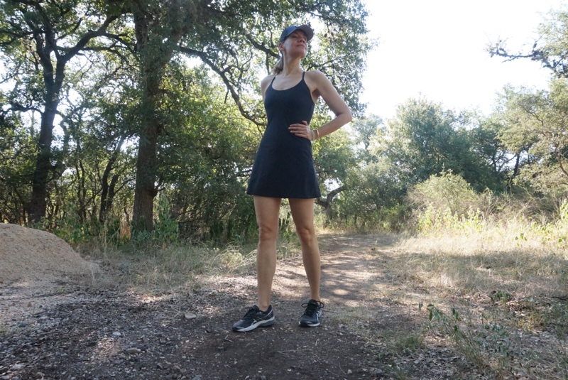 a woman in an exercise dress and sneakers running on a trail