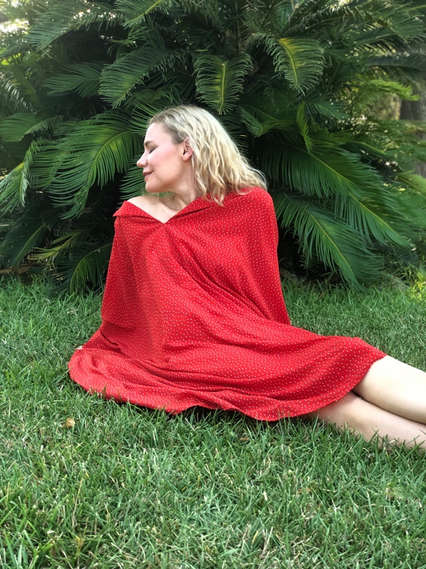 a woman sits on green grass in a Red Caftan
