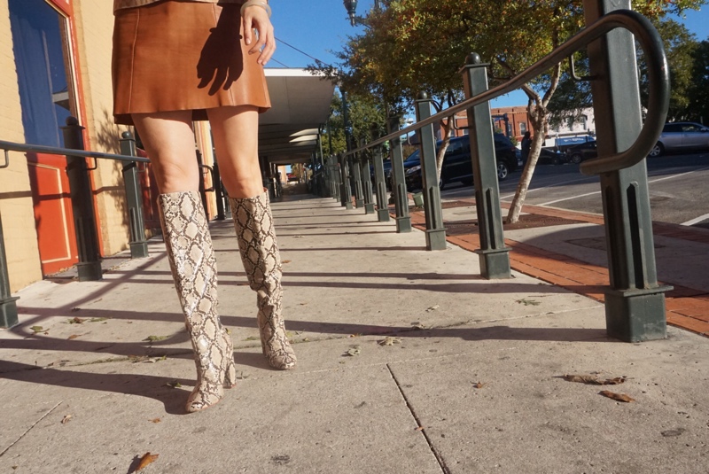 a close up of a woman's legs in snakeskin boots and a brown leather mini skirt