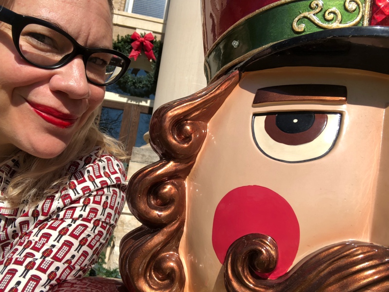 a close up selfie of a woman in red lipstick and the head of a giant nutcracker