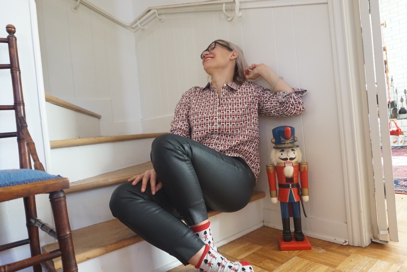 a woman in black leather pants and toy soldiers button down sits on stairs by a nutcracker stand