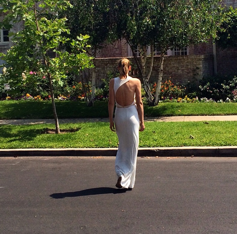 the back of a woman in a white dress in front of a house