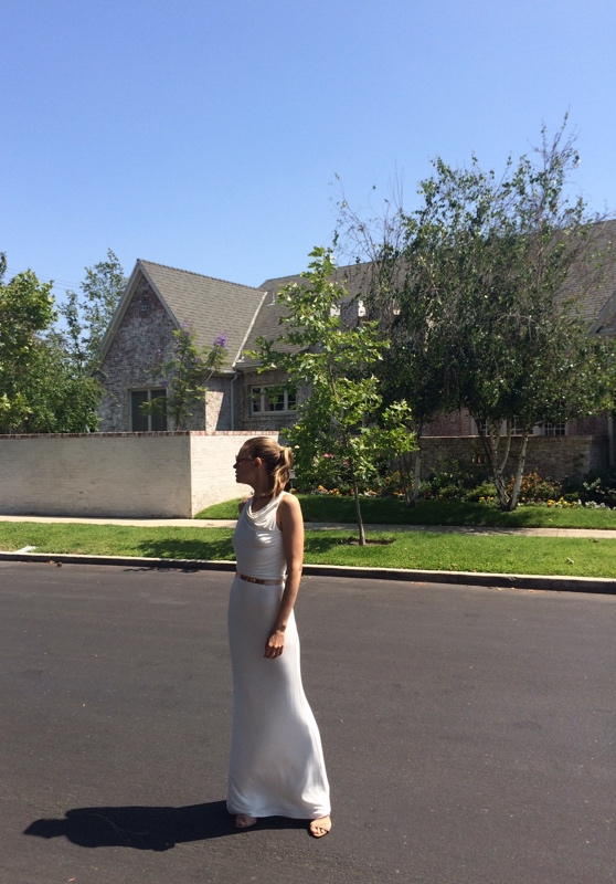 a woman in a white dress in front of a house