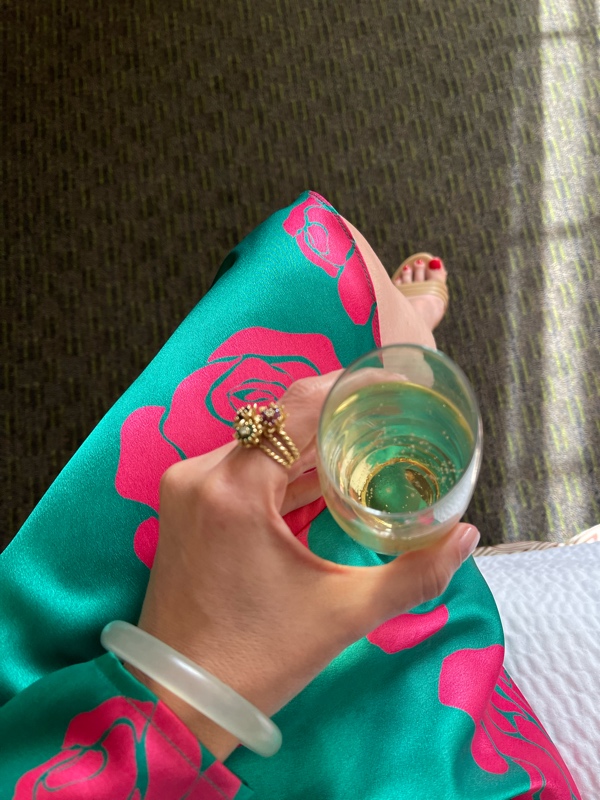 a woman with a glass of champagne in a green silk dress with pink roses on it