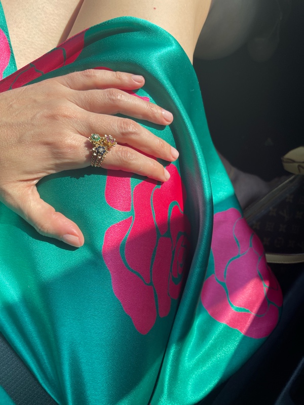 a woman in a green silk dress with pink roses on it, close up of floral rings