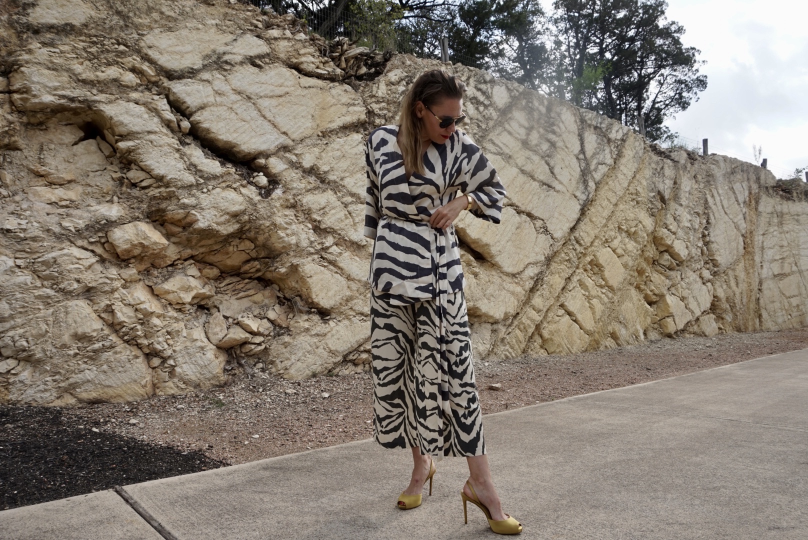 a woman in zebra print in front of a stone wall