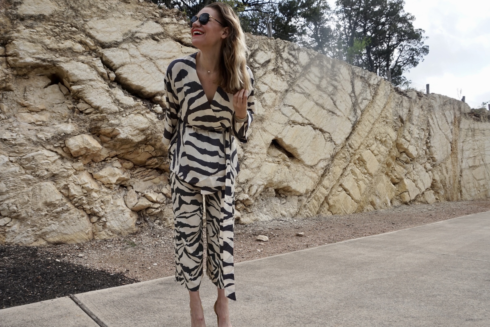 a woman in a zebra print suit in front of a stone wall