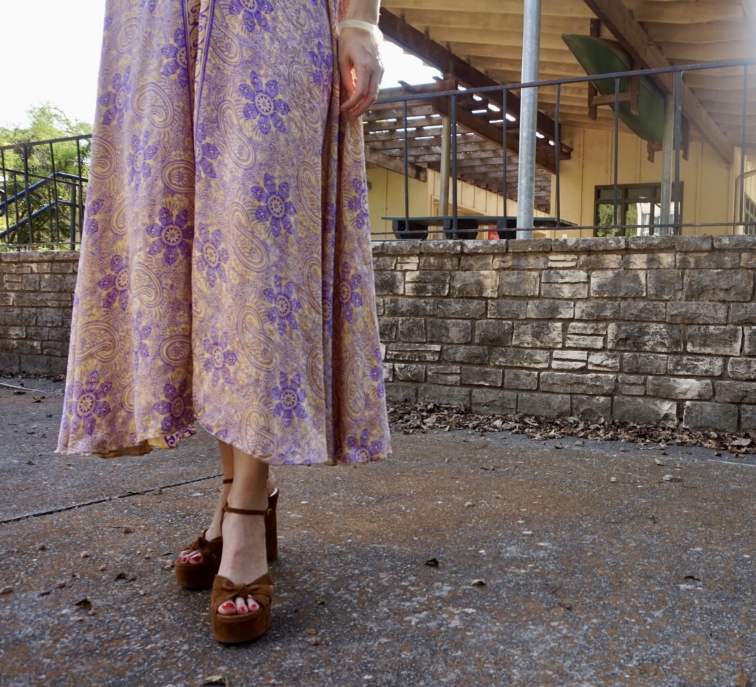 a woman in a gold and purple caftan and brown platforms