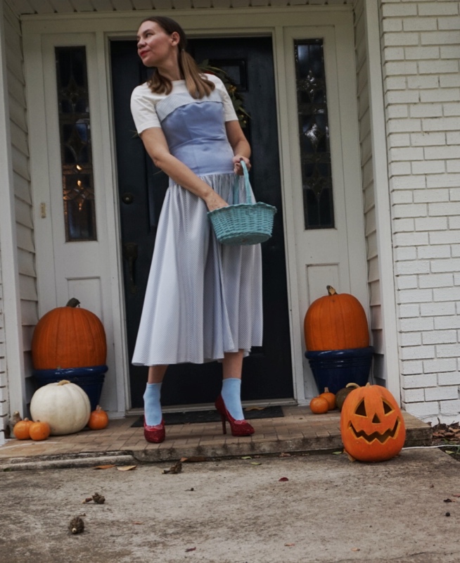 a woman in pumpkins in ruby red slippers in a blue striped dress with a white shirt