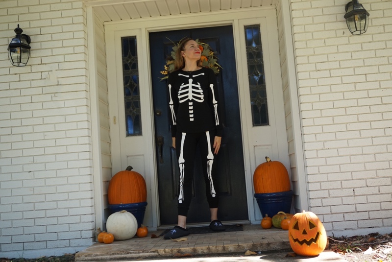 a woman in skeleton pjs with pumpkins