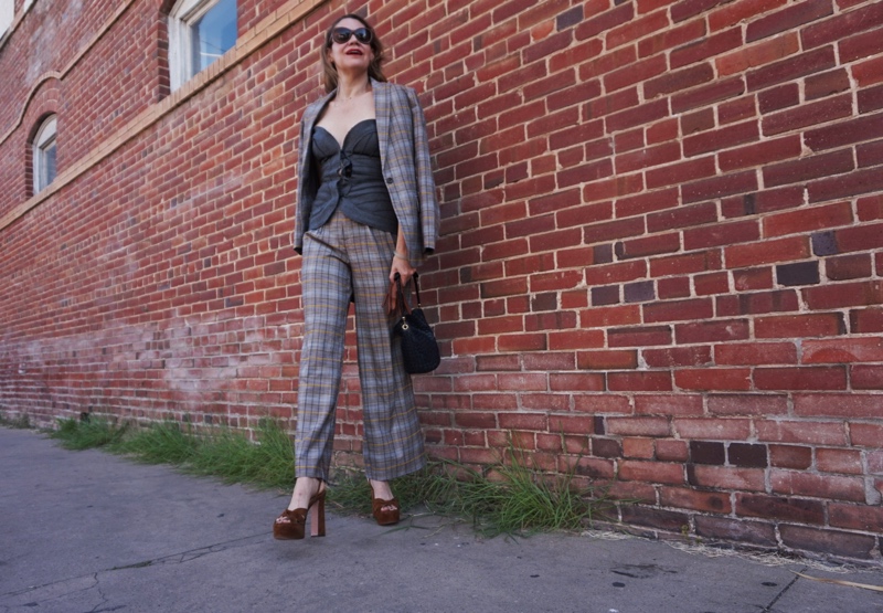 a woman in a plaid suit and grey corset with platforms