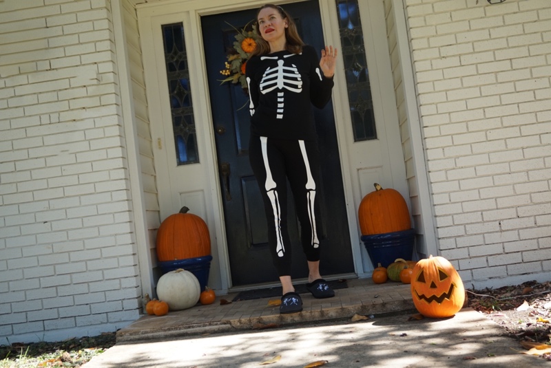a woman in skeleton pjs surrounded by pumpkins