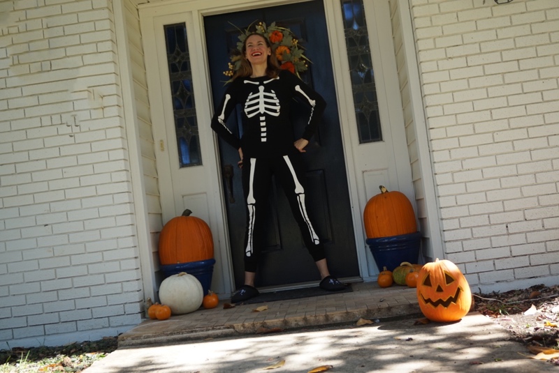 a woman in skeleton pjs and pumpkins
