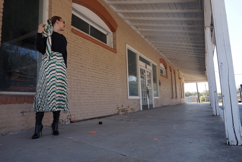 a woman in striped skirt and sweater and boots 