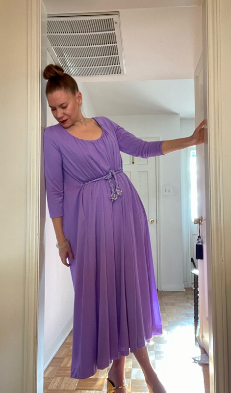 a woman in a purple hostess dress leaning against a wall