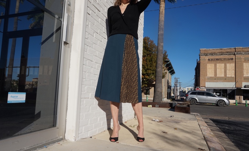 a woman in a blue wool skirt and a black sweater and heels