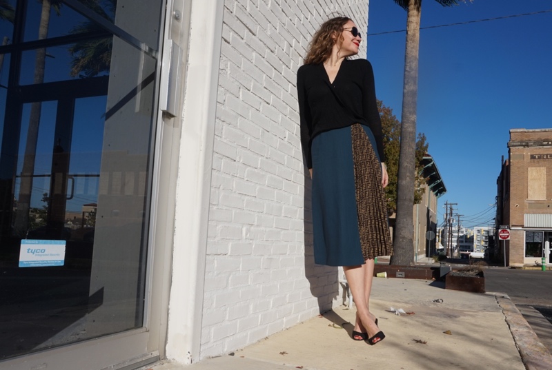 a woman in a blue wool skirt and a black sweater and heels 