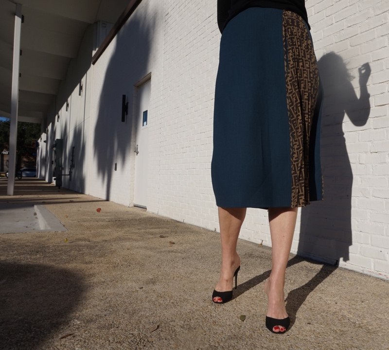 a woman in blue wool skirt and black sweater and heels