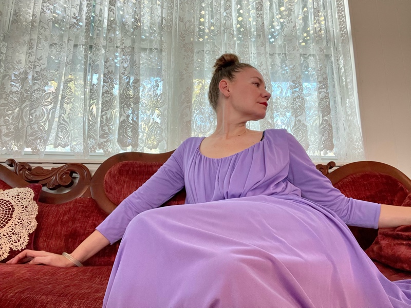a woman in a purple hostess dress on a red couch
