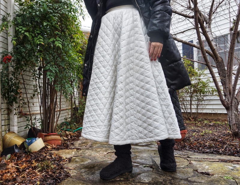 a woman in a white and black puffer skirt, black puffer jacket, and Black Uggs