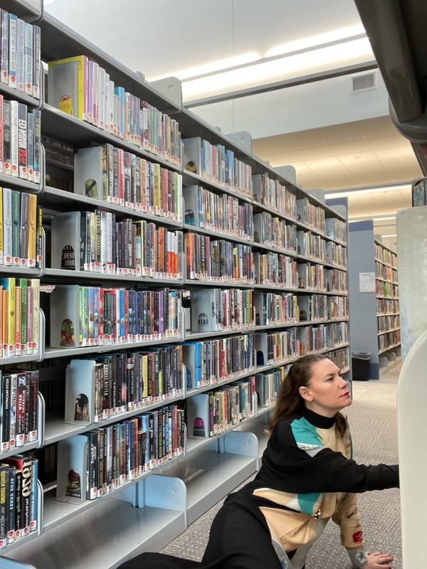 a woman in library stacks in a dress with Marilyn Monroe on it 