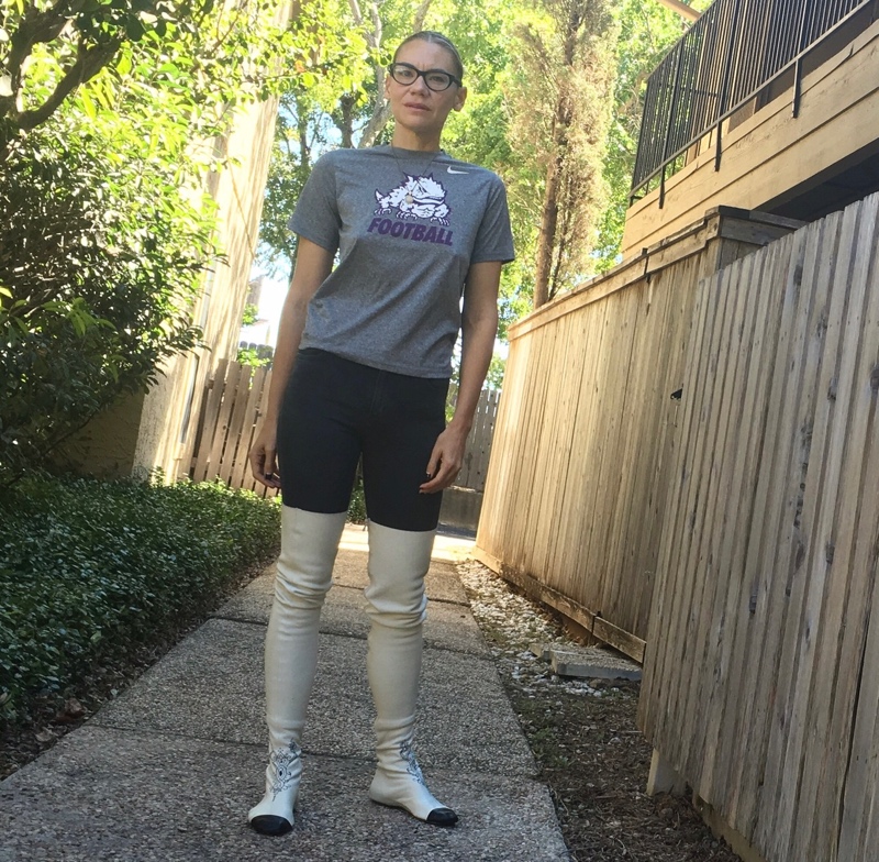 a woman in a TCUFootball shirt, jeans, and over the knee white Chanel flat boots