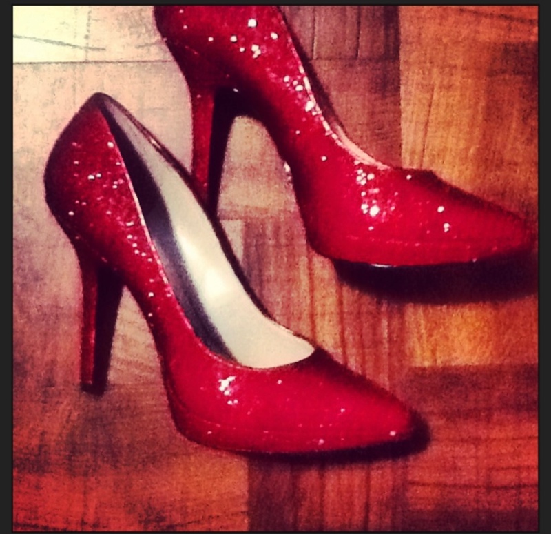 a close up of red sparkly heels on wood floor