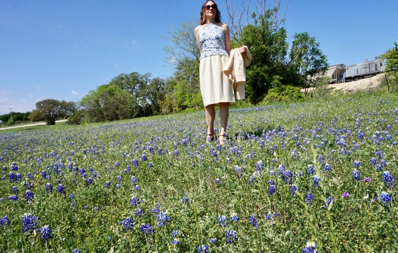 a woman in a yellow skirt suit with a blue and white halter top in a filed of wildflowers