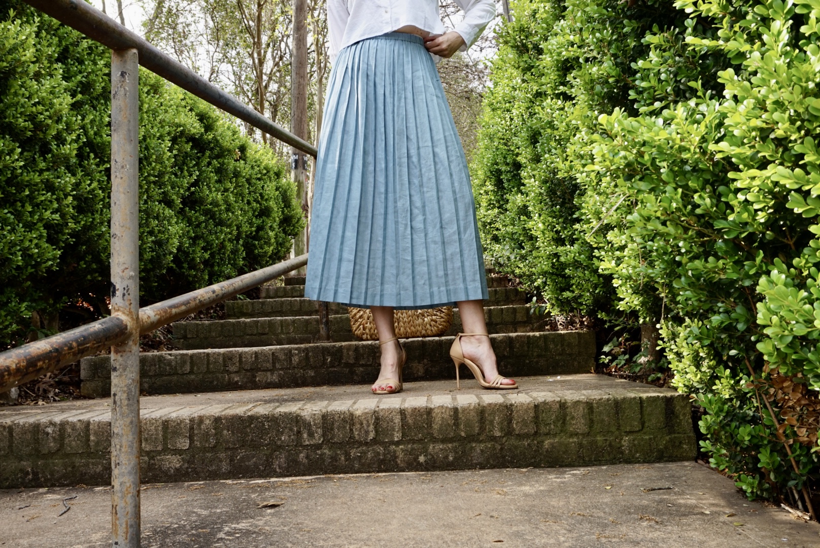 a woman in a cropped white button down and blue skirt on stairs
