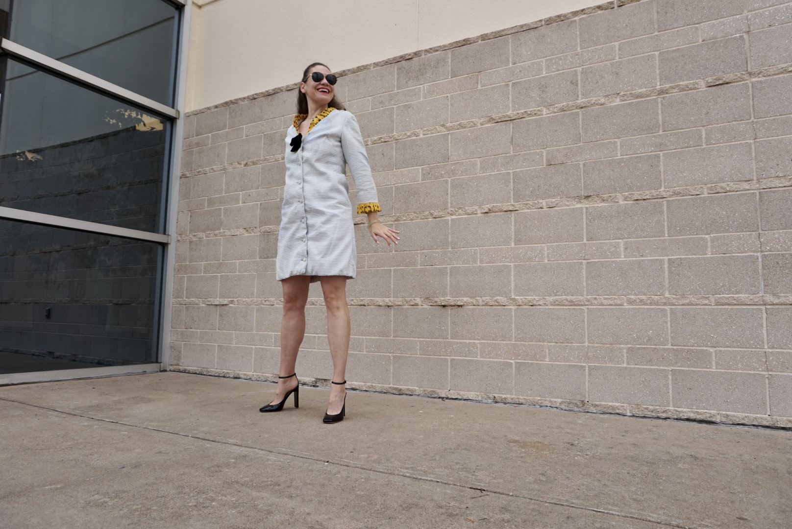 a woman in a white coat dress with a yellow collar and cuff ruffle, black patent Mary Jane heels