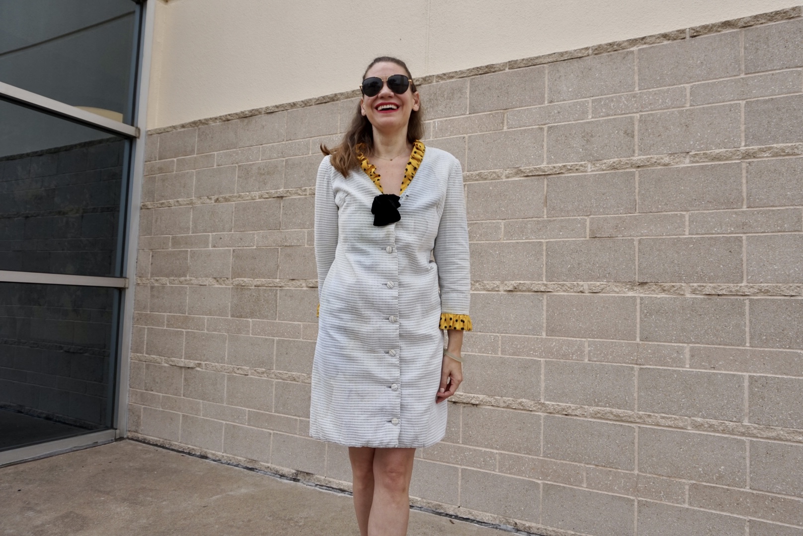 a woman in a white coat dress with yellow collar and cuff ruffles and a velvet bow