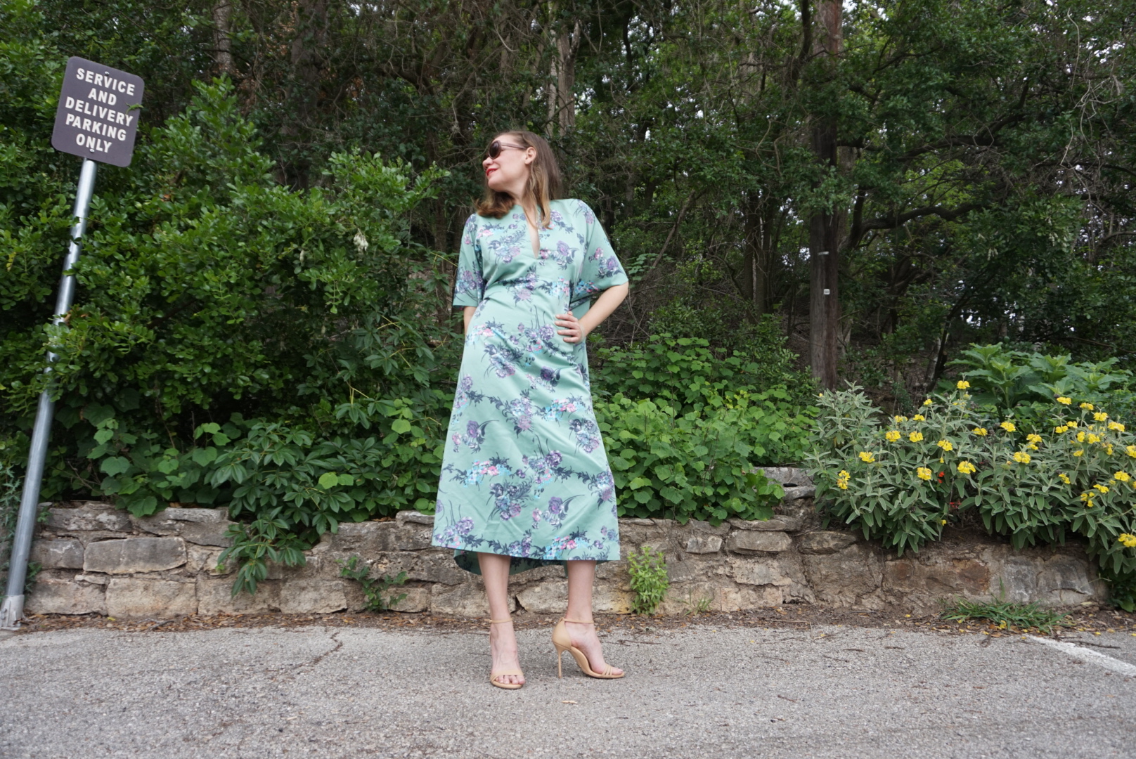 a woman in a green floral caftan and heels 