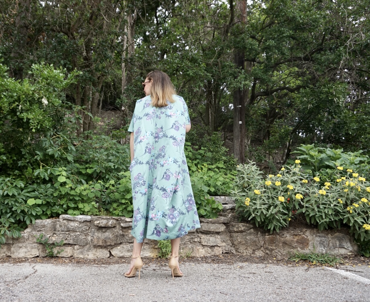 a woman in a green floral caftan and heels