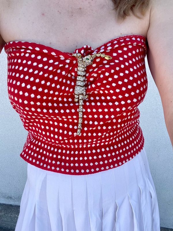 an articulated leopard pin holding together a red and white tube top over a white skirt