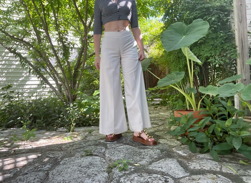 a woman in a cropped cardigan in blue and white stripe and white crop pants and brown sandals 