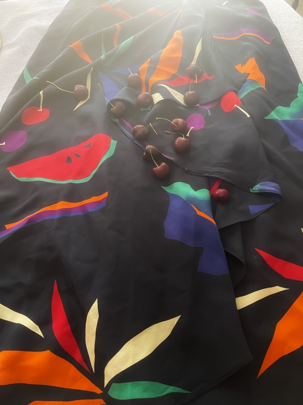 A black silk skirt with fruit graphics such as watermelon, cherries, apples, etc, with real cherries on top